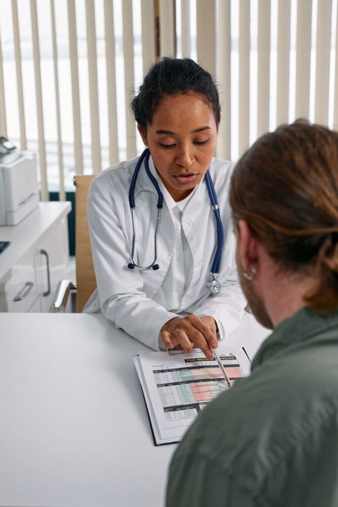 Black female doctor reviewing a health chart with a patient during consultation